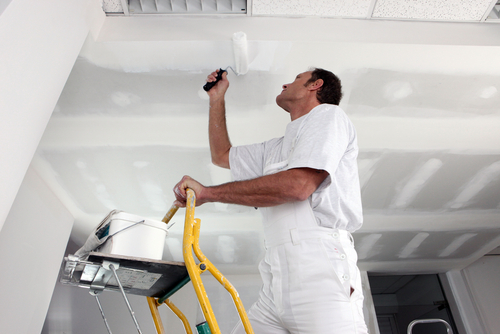 Painter using a roller to paint ceiling white